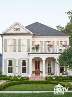 a large white house with lots of windows and bushes in front of the door area