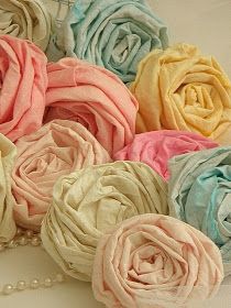 a bunch of fabric flowers sitting on top of a white table cloth covered in pearls