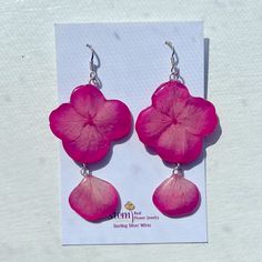 the pink flower earrings are hanging from silver earwires on a white card board