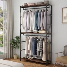 a clothes rack with several shirts hanging on it and a chair next to it in front of a window