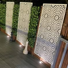 an outdoor deck with decorative privacy screens and lights on the sides, along with potted plants