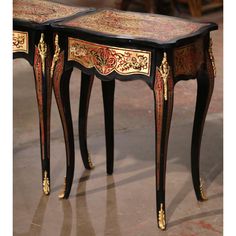 two black and gold painted tables with ornate designs on the top one is turned upside down