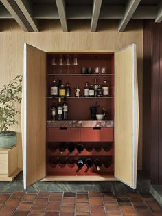 an open wine cabinet with bottles and glasses on the bottom shelf in front of it