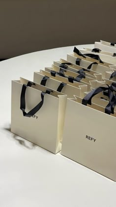 several bags are lined up on a table with black ribbon around the handles and sides