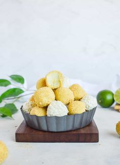 a cupcake tin filled with white and yellow cake batter bites next to limes