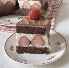 a piece of chocolate cake with strawberries on top and another slice in the background