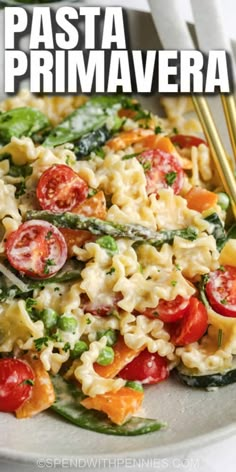 pasta prima primavera with tomatoes, asparagus and spinach on a white plate