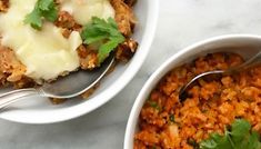 two white bowls filled with rice and meat covered in gravy, garnished with cilantro