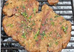 two steaks cooking on top of an open grill