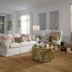 a living room with white furniture and wood flooring in it's center area