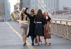 three women walking across a bridge with their arms in the air