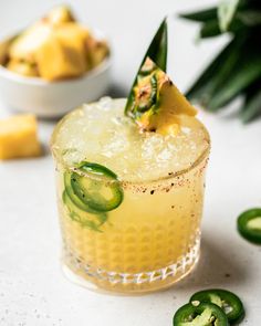 a close up of a drink on a table with sliced jalapenos in the background