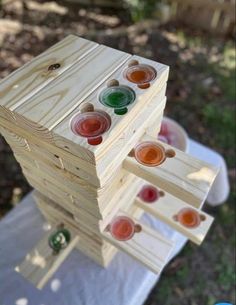 a stack of wooden pegs with different colored buttons on them sitting in the grass