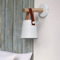 a white lamp hanging from the side of a wall next to a bed with pillows