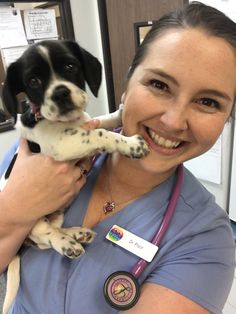 a woman in scrubs holding a black and white dog