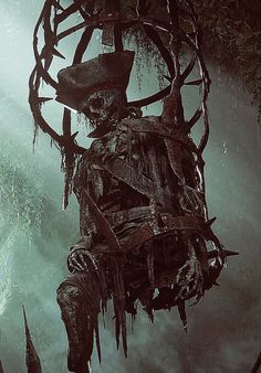 a creepy skeleton hanging from a tree in the dark with an evil hat on it's head