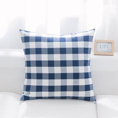 a blue and white checkered pillow sitting on top of a couch next to a window