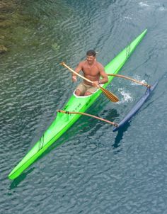 a man in a green kayak paddles through the water with two oars