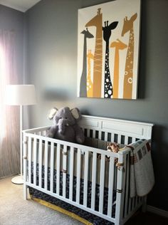 a baby crib with a stuffed animal in it and a giraffe painting on the wall