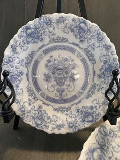 an ornate blue and white plate with iron stand on the ground next to it,