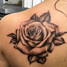 a black and white rose tattoo on the back of a woman's shoulder