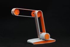 an orange and white desk lamp on a black background