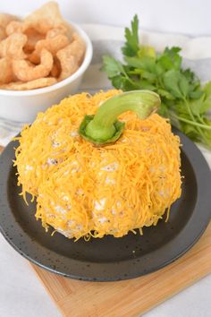 a black plate topped with cheese covered food next to a bowl of fried onion rings