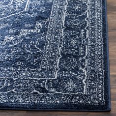 a blue area rug with an intricate design on the top and bottom, in front of a wooden floor