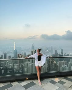 a woman standing on top of a tall building next to a large cityscape