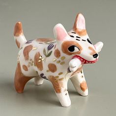 a ceramic figurine of a dog with spots on it's face and tail