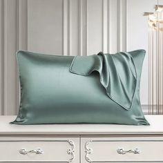 a pillow with a bow on it sitting on top of a white dresser next to a lamp