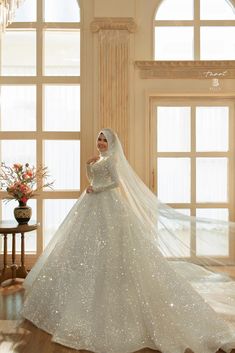 a woman in a white wedding dress standing on a wooden floor next to large windows