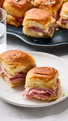 ham and cheese sandwich cut in half on a plate next to a glass of water