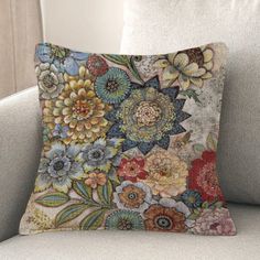 a pillow on a couch with flowers in the middle and one flower is multicolored