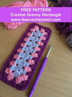 a crochet granny next to yarn and a ball of knitting needles on a table