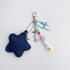 two key chains with charms attached to them on a white surface, one has a teddy bear and the other is a star