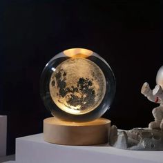 an astronaut looking at the moon in a glass ball on a stand with rocks and candles