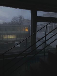 the view from inside an apartment building at night, looking out onto a parking lot