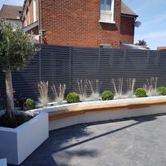 a modern garden with wooden bench and white planters