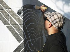 a man is painting the side of a wall with black and white designs on it