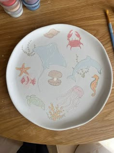 a plate with sea animals painted on it next to watercolors and paintbrushes