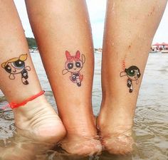 two people with matching tattoos on their legs standing in the water near each other's feet