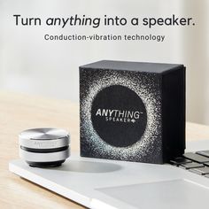 an open laptop computer sitting on top of a wooden table next to a black and white speaker