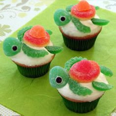 three cupcakes with white frosting and red flowers on them, sitting on top of a green napkin