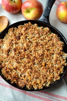 an apple pie in a cast iron skillet next to apples