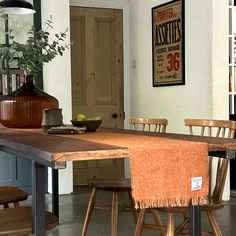 a wooden table with chairs and a vase on it