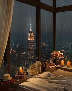 a bedroom with a view of the empire building at night and candles on the bed