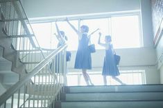 three women in blue dresses are walking down the stairs with their arms up and one woman is holding her hand up