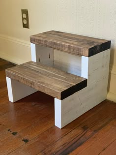 a wooden bench sitting on top of a hard wood floor next to a white wall