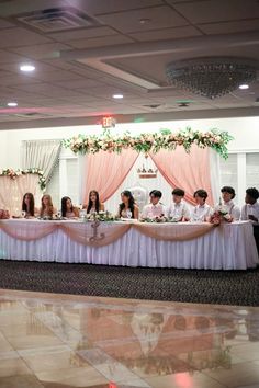 a group of people sitting at a long table with flowers on the headbands